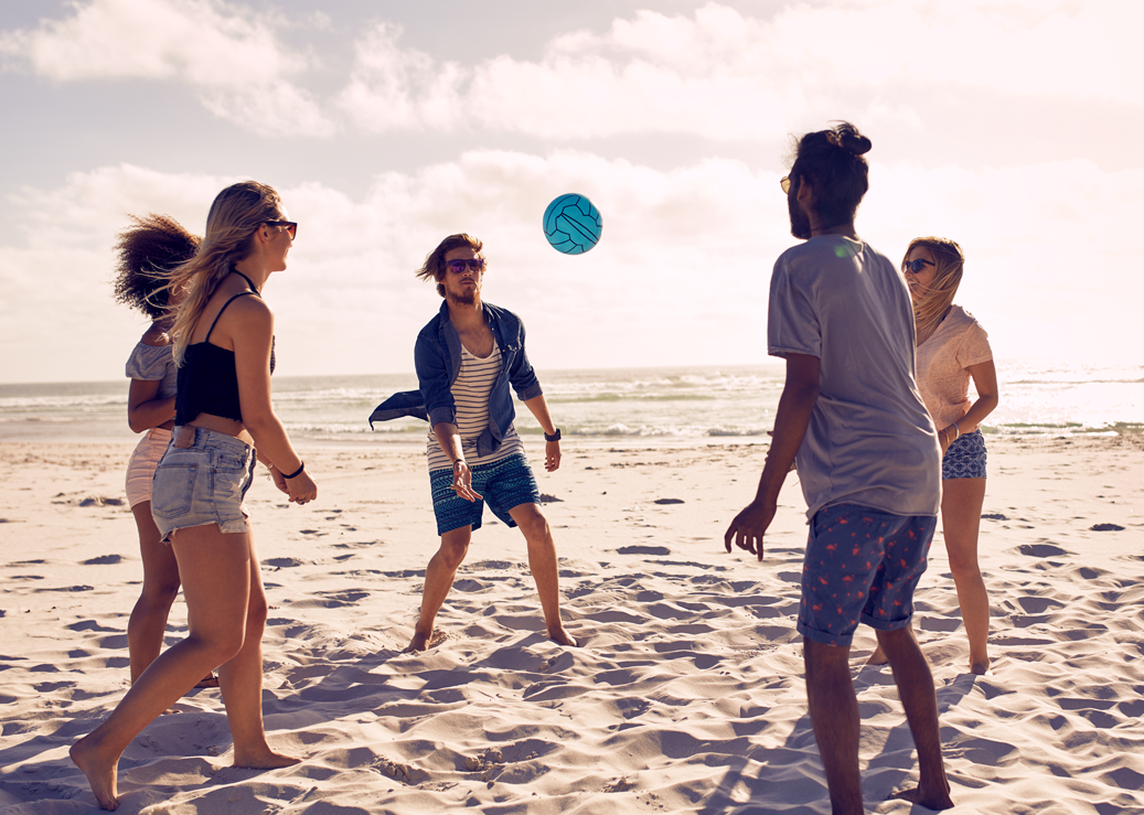 a group of people playing with a frisbee on the beach