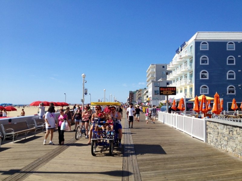 a group of people walking along a pier next to buildings