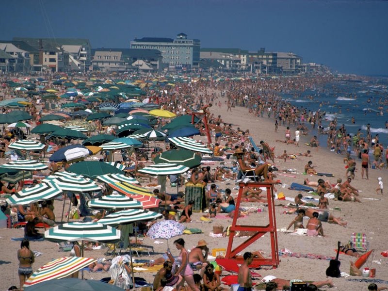 a crowded beach with many people and umbrellas